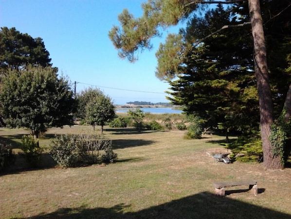 A grassy area with a wooden bench, trees, and a view of a body of water. - Sarzeau: House / Villa - Suscinio- Sarzeau (Sarzeau)