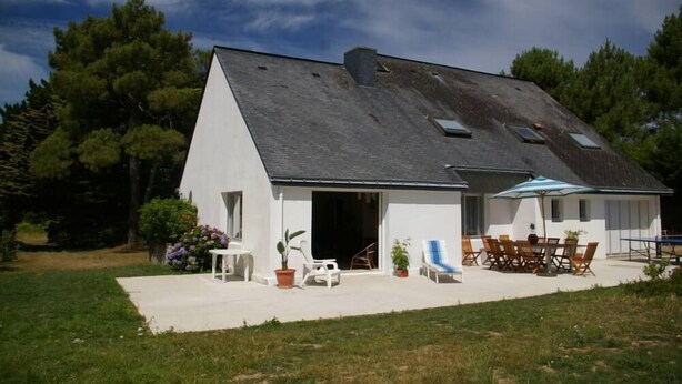 Une maison moderne avec un toit en pente, une terrasse dotée de mobilier d’extérieur et un jardin.