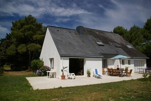 A modern house with a sloped roof, a patio with outdoor furniture, and a garden area. - Sarzeau: House / Villa - Suscinio- Sarzeau (Sarzeau)