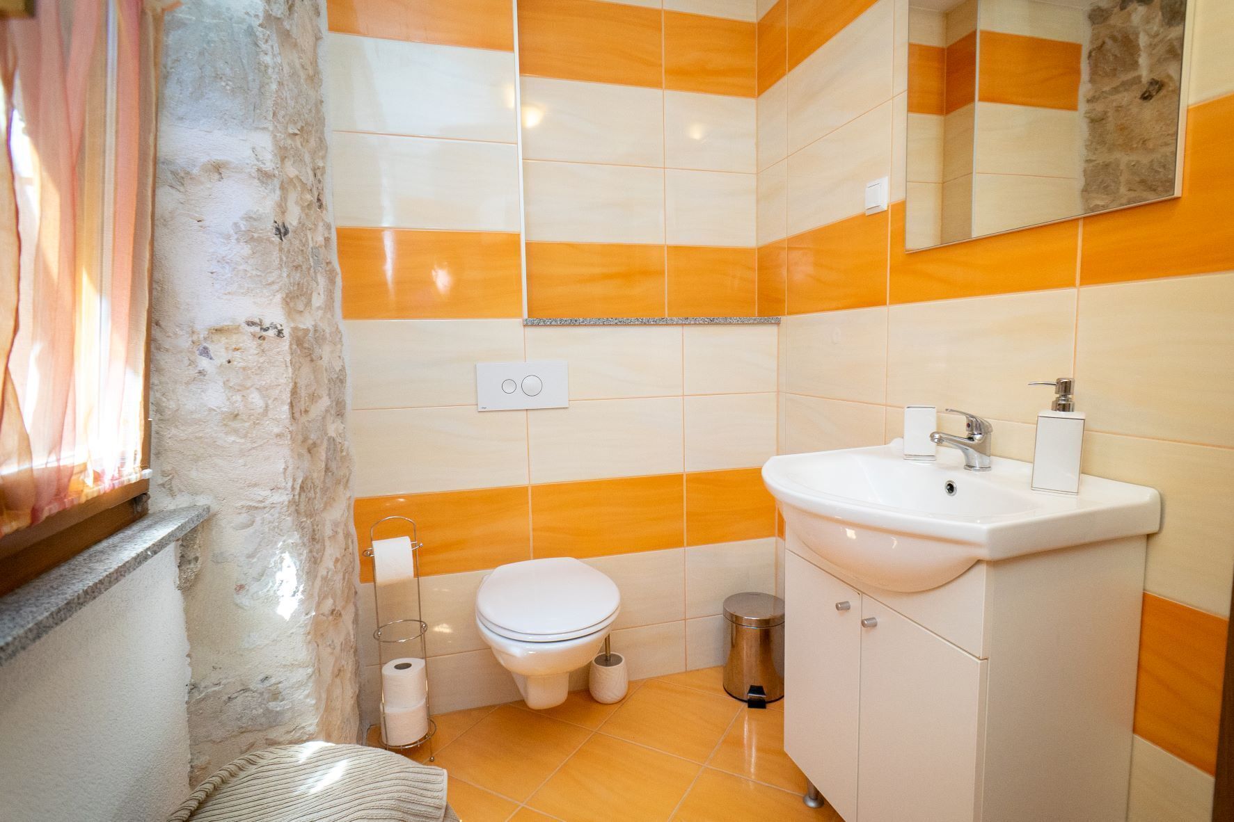 A bathroom with a toilet, sink, and mirror.