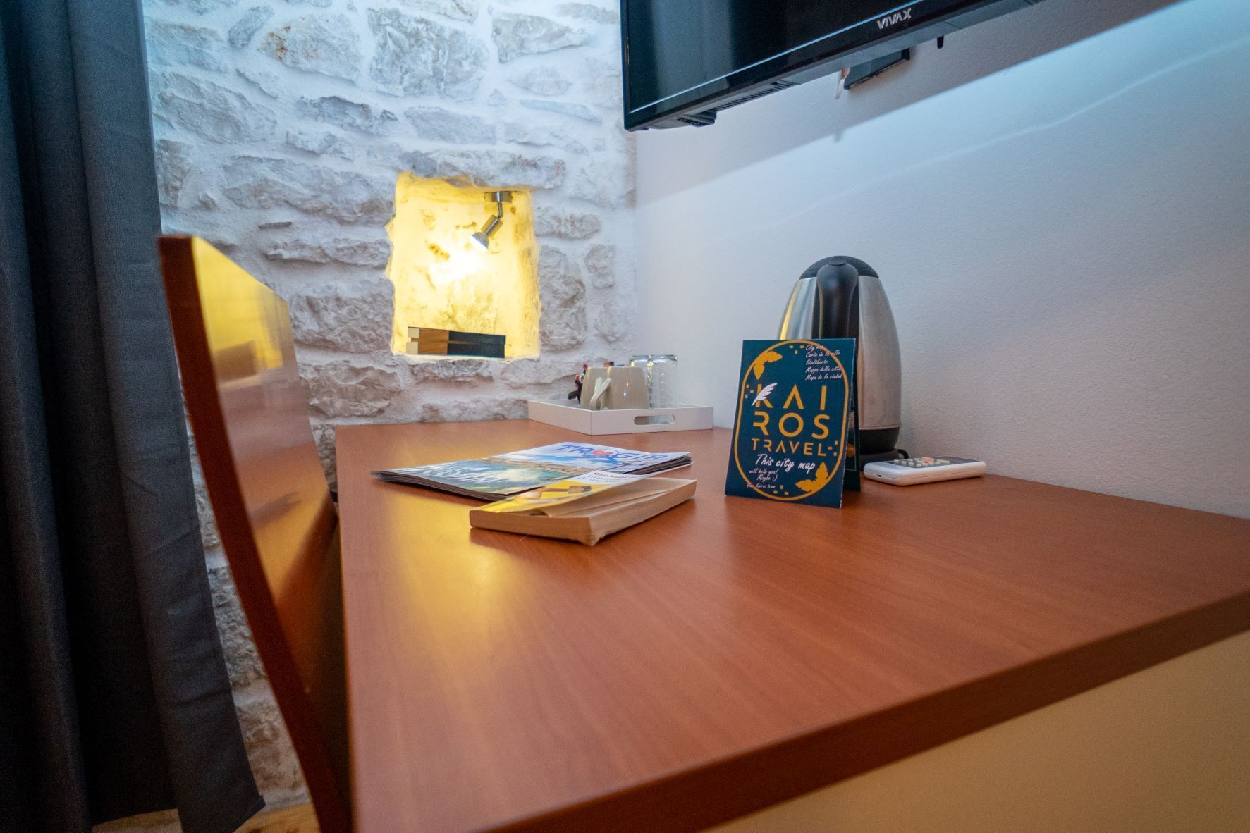 A wooden desk with a city map, a remote control, and a lamp.