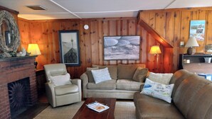 Ein gemütliches Wohnzimmer mit Kamin, Ledersofas und Holzvertäfelung.