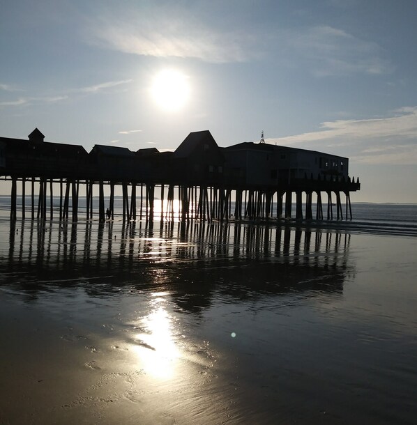 A pier with buildings extending over the water, reflecting the sun. - Charming Cottage 5 min walk to beach & 8 min. walk to The Pier !!! (Old Orchard Beach)