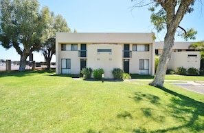 Stunning two-story residence with a flat facade and symmetrical windows, surrounded by a serene lawn and mature trees.