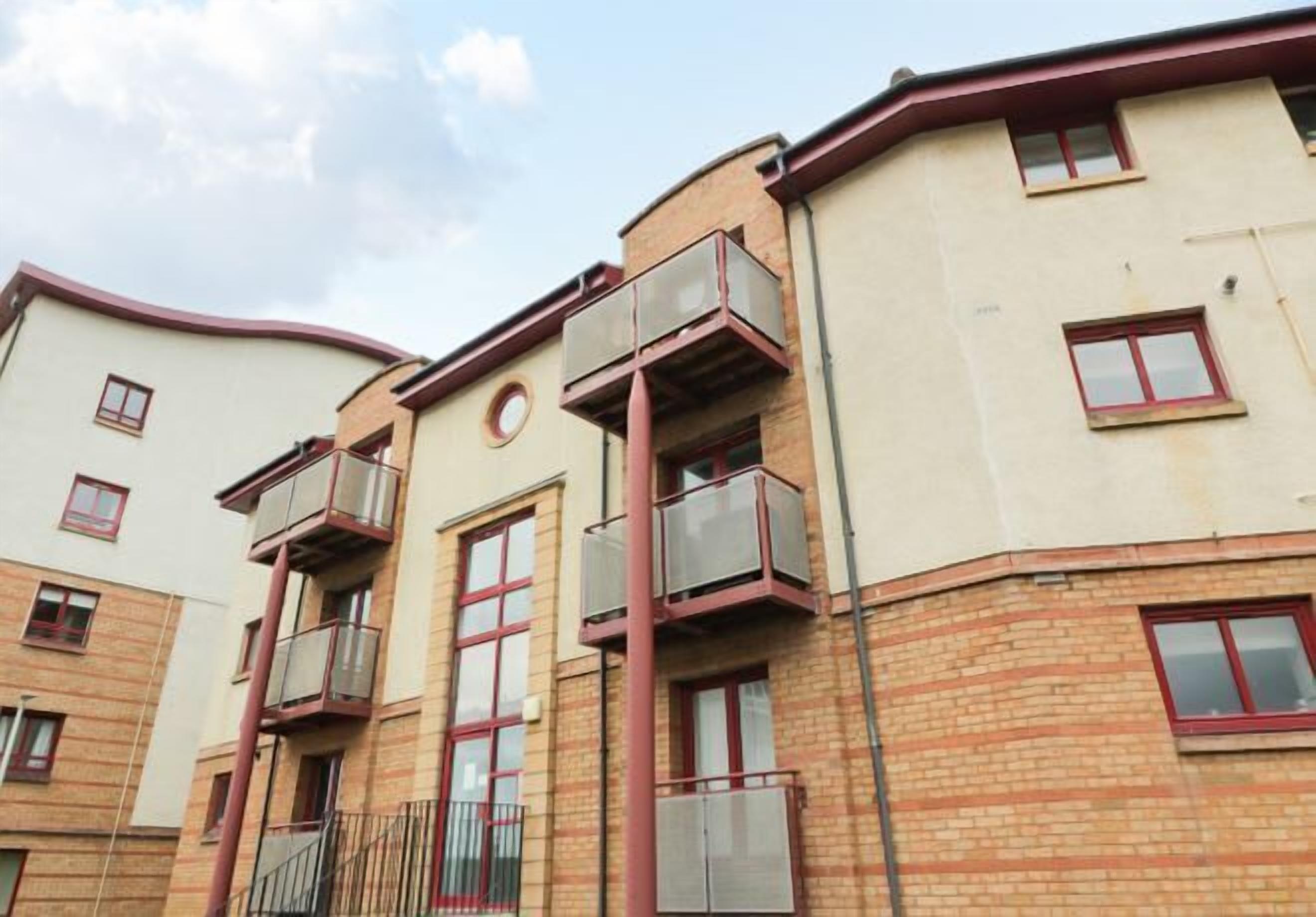 Un edificio residenziale a più piani con balconi, finestre e facciata in mattoni.