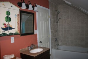 Een bad/douchecombinatie, een haardroger, handdoeken, toiletpapier