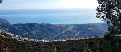 A stone wall with a view of a coastal landscape and distant city.