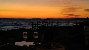 A sunset view from a seaside restaurant with two wine glasses on a table. - Casa Llebeig - Apartament with panoramic Sea view of Cala en Porter - Menorca (Cala en Porter)