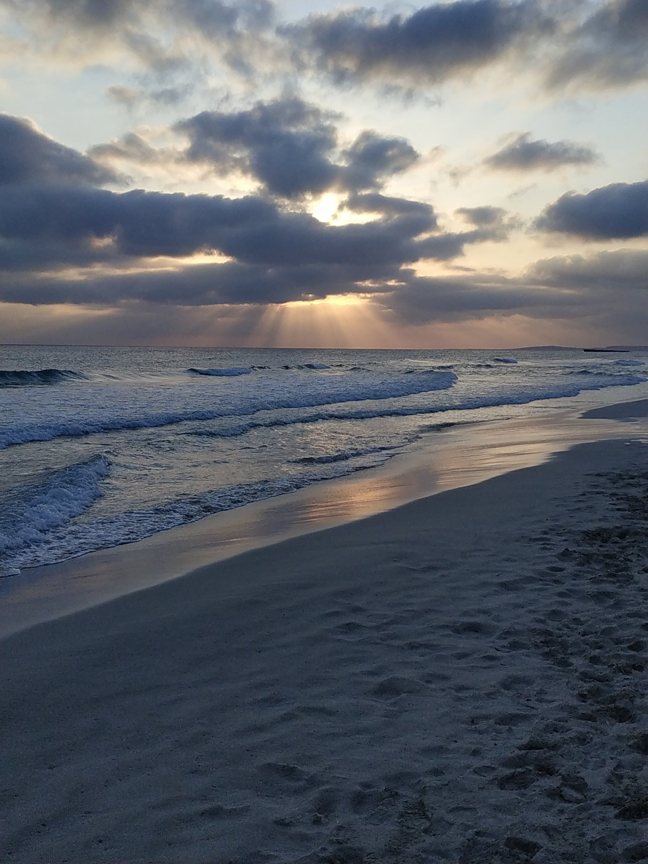 Une plage avec des vagues et un ciel nuageux.