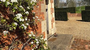 A brick building with a garden area, a paved driveway, and a hedge.