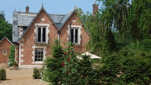 A brick house with a gabled roof, a front entrance, and a small balcony.