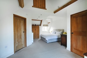 A bedroom with a bed, wooden wardrobe, and a window with curtains.