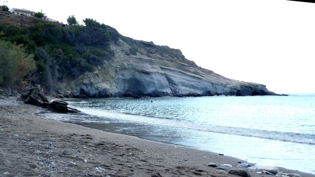 Una spiaggia rocciosa con una scogliera e una vista limpida sul mare.