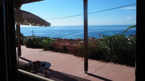 Una terrazza con un tavolo apparecchiato per la colazione, con vista su un panorama mozzafiato sull'oceano e sul paesaggio costiero.