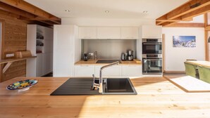 A modern kitchen with white cabinets, a stainless steel sink, and wooden beams.