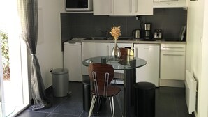 A modern kitchen with white cabinets, a glass dining table, and a stainless steel sink.