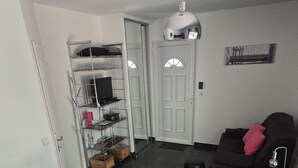 A modern living room with a round dining table, a black sofa, and a small side table with a lamp.