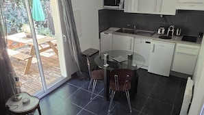A modern kitchen with white cabinets, a round glass table, and a dining area with chairs.