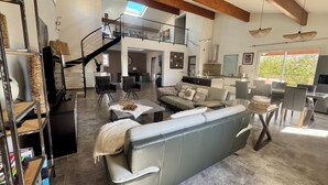 A spacious living area with a high ceiling, a staircase, and a kitchen area. - Villa PALOMA PISCINE Chauffée SPA between Narbonne and Béziers- 15 km VALRAS PLAGE (Colombiers)