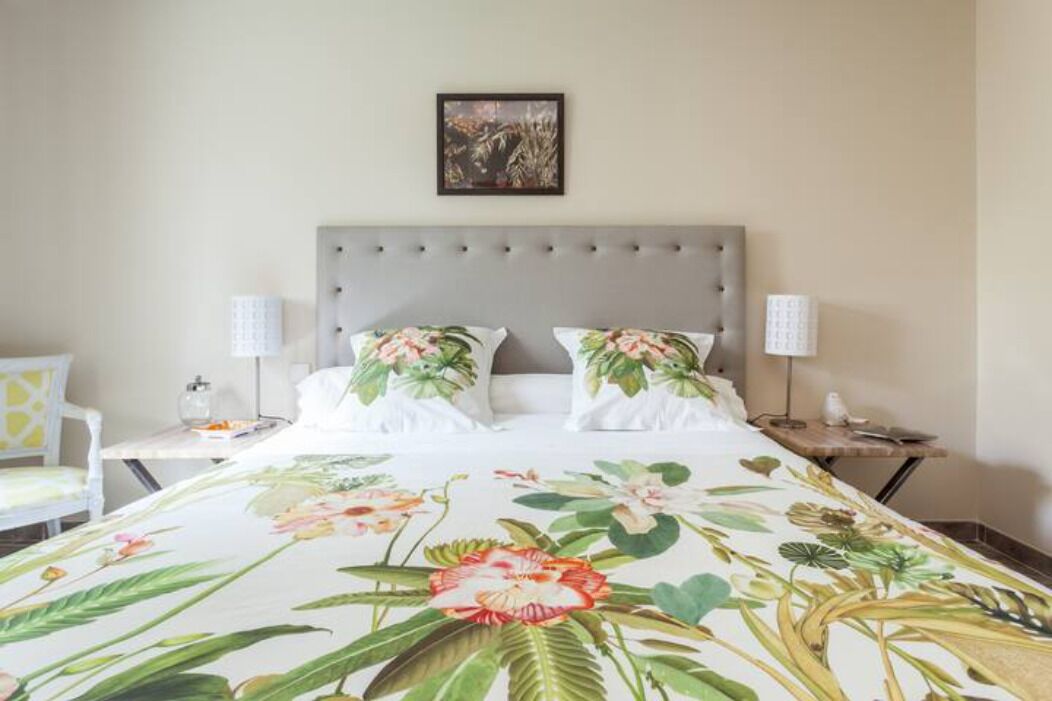 Une chambre d’hôtel avec un lit, deux tables de chevet, une chaise et un tableau accroché au mur.