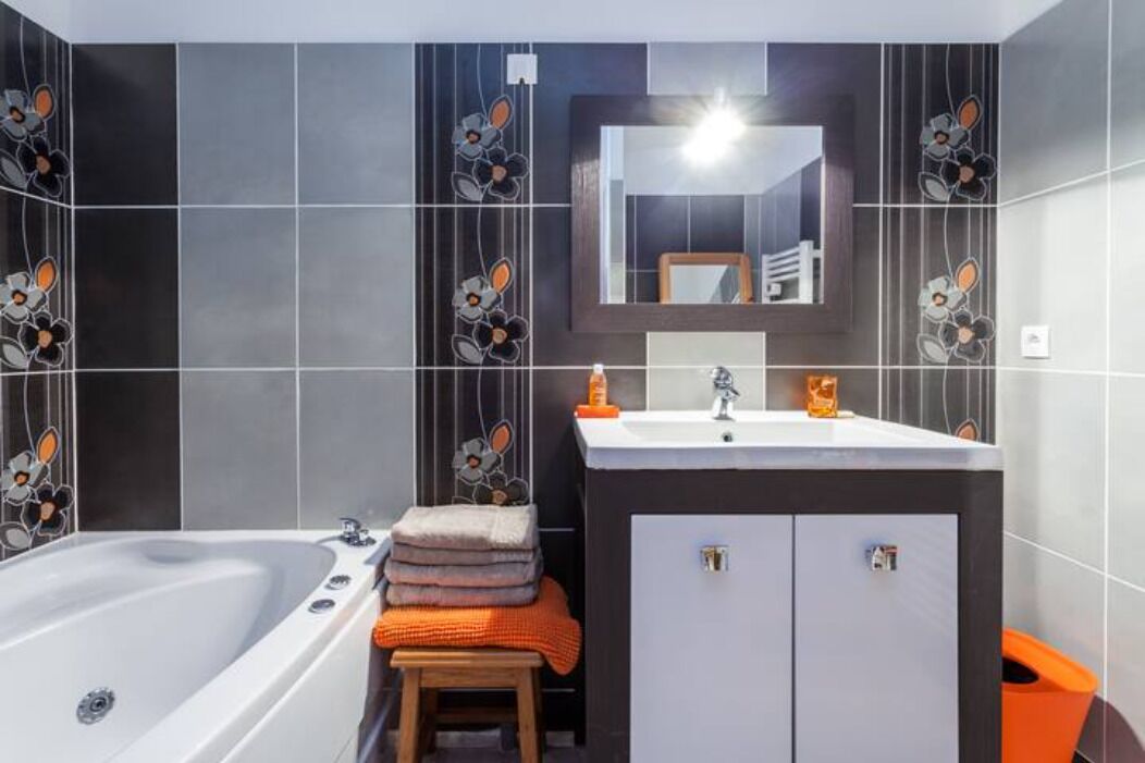 A modern bathroom with a bathtub, vanity, and a mirror.