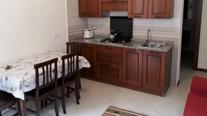 Une cuisine compacte dotée de meubles en bois, d’une cuisinière à gaz, d’un évier et d’un coin repas avec une table et des chaises.