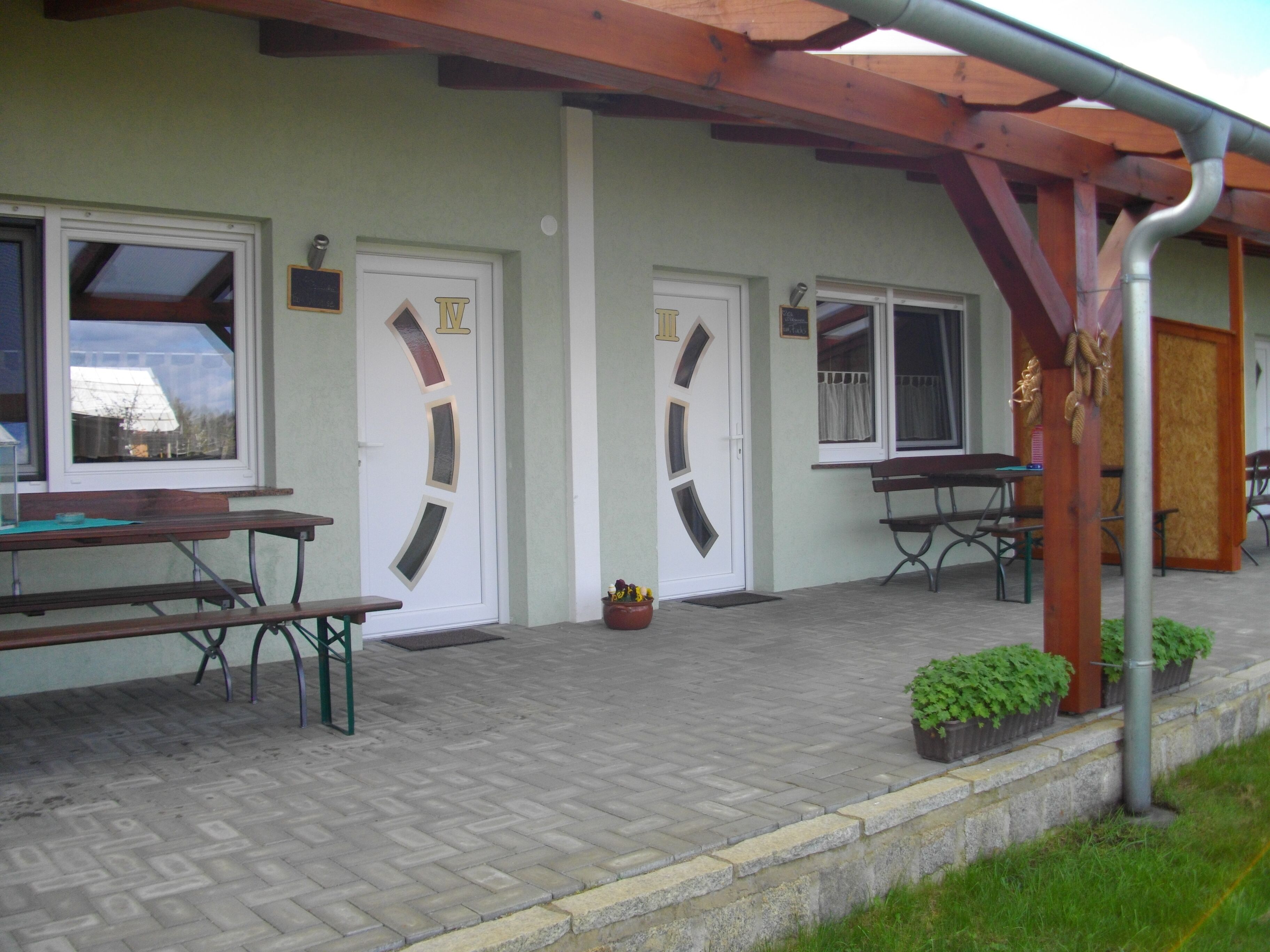 A building with a covered patio, two doors, and outdoor seating.