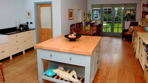 A spacious kitchen with wooden cabinets, a central island, and a dining area with a view of the garden.