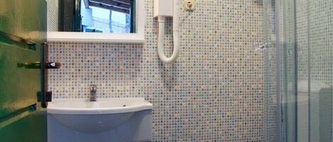 Ein Badezimmer mit gefliestem Rücksprüher, einem Waschbecken, einer Toilette und einer Duschkabine.