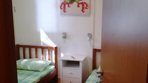 Ein Schlafzimmer mit zwei Einzelbetten, einem Nachttisch, einer Wand-Klimaanlage und einem Froschgemälde.