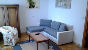 Ein Wohnzimmer mit einer Couch, einem gemusterten Sessel, einem Couchtisch und zwei an der Wand befestigten Bildern.