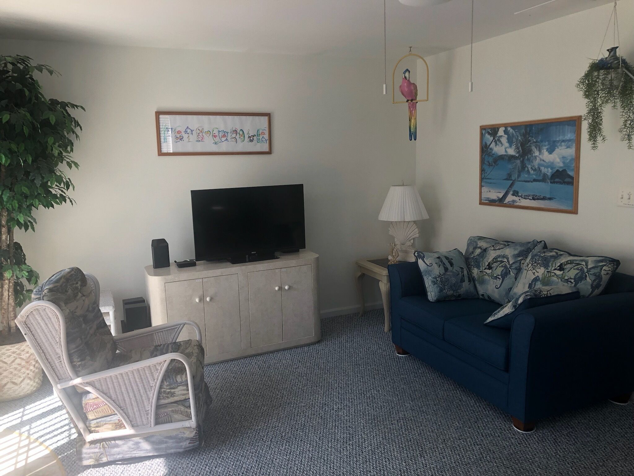 A living room with a television, a sofa, a chair, a lamp, and wall art.