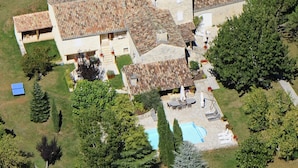 Una casa grande con piscina, rodeada de árboles y jardín.