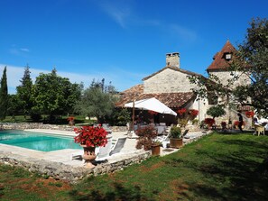 Un bâtiment en pierre doté d’une piscine, d’un espace extérieur aménagé et de plantes en pot.