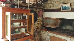 Una cocina rústica con paredes de piedra, armarios de madera y un horno empotrado.