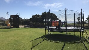 A playground with a trampoline, a slide, and a climbing structure.