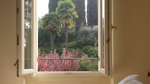 Un dormitorio con vista al jardín por la ventana, una cama y una toalla enrollada.