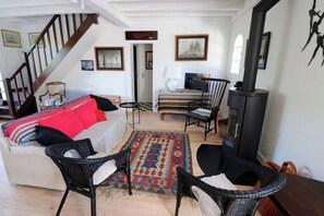 Una sala de estar acogedora con un sofá, sillas, una alfombra, una chimenea y una escalera.