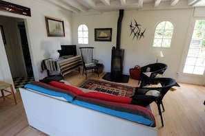 A cozy living room with a sofa, chairs, a fireplace, and artwork on the walls.