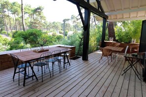 A wooden deck with a table and chairs, surrounded by greenery and trees. - Lovely country house close beach A0384 (Cap Ferret / Piraillan)