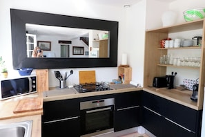 A modern kitchen with a black countertop, stainless steel appliances, and a large mirror above the sink.