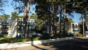 A multi-story residential building with balconies, surrounded by trees and a clear sky. - Your holiday is just 100m from award winning beaches on Sandbanks peninsular. (Poole)