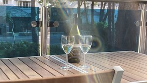 A wooden table with a bottle of wine and two glasses on a balcony. - Your holiday is just 100m from award winning beaches on Sandbanks peninsular. (Poole)