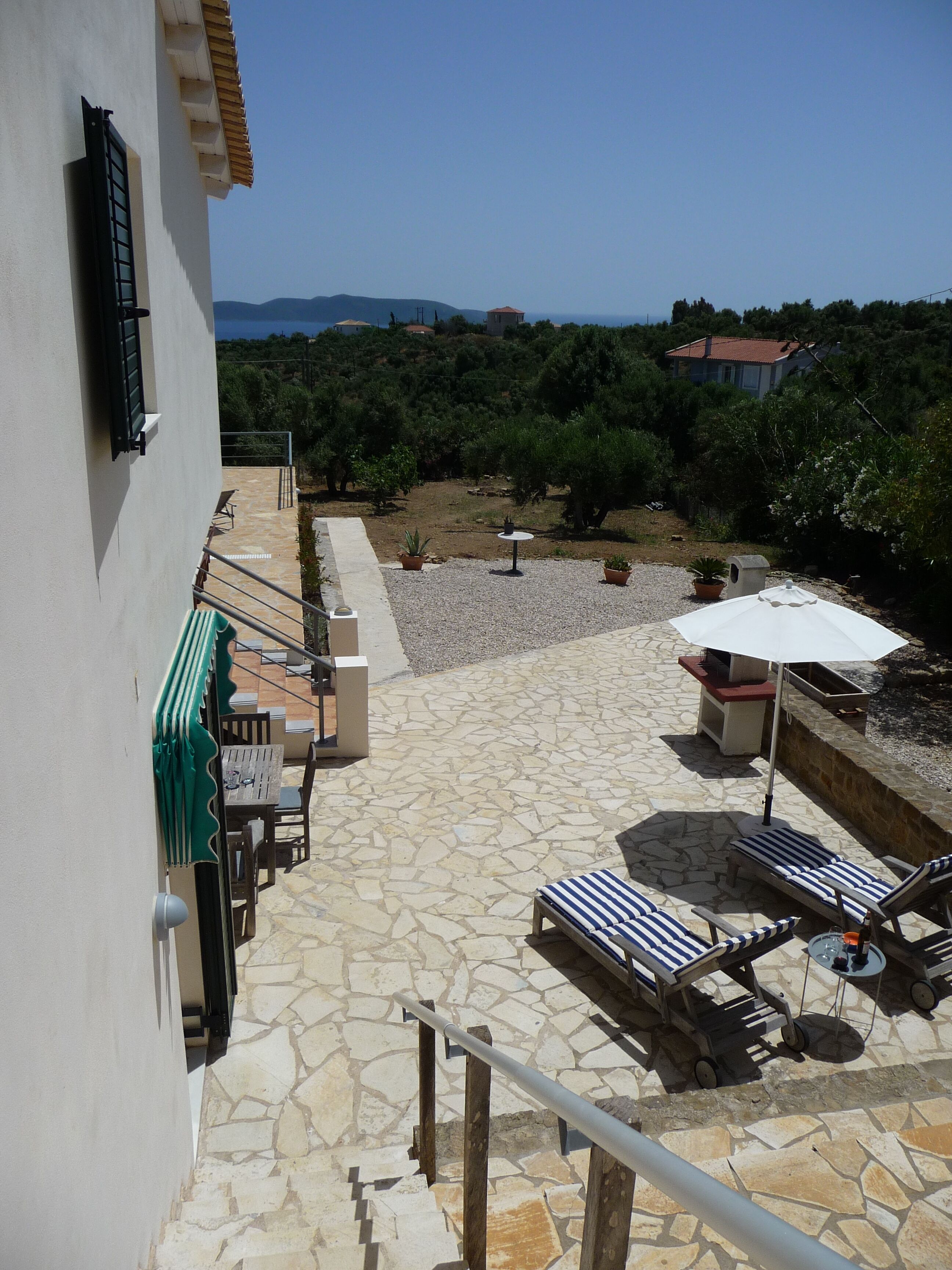 Eine Terrasse mit Steinboden, Gartenmöbeln und Blick auf die umliegende Landschaft.