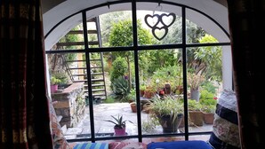 A room with a large arched window overlooking a garden. There is a ladder leading to a wooden deck outside. - Apartment With Large Terrazzo And Garden In Tranquil Village internet wifi (Costa Carnara)