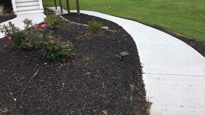 Un jardin aménagé avec un chemin sinueux, une terrasse blanche et une pelouse verdoyante.