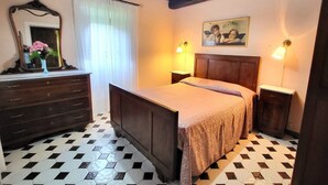 A bedroom with a wooden bed, a dresser, a mirror, and a painting on the wall. - 4 bedroom, 2 bathroom converted Mill house with private pool.  Outdoor kitchen! (Poggio Camporgiano)