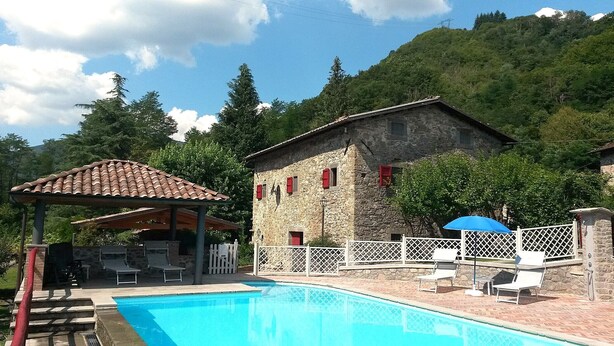 A stone building with a pool, outdoor seating, and a pergola. - 4 bedroom, 2 bathroom converted Mill house with private pool.  Outdoor kitchen! (Poggio Camporgiano)