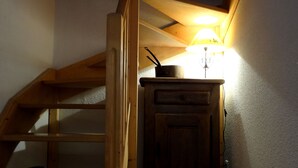 Eine Holztreppe führt zu einem Schlafzimmer mit Erker und einer kleinen Küchenzeile.