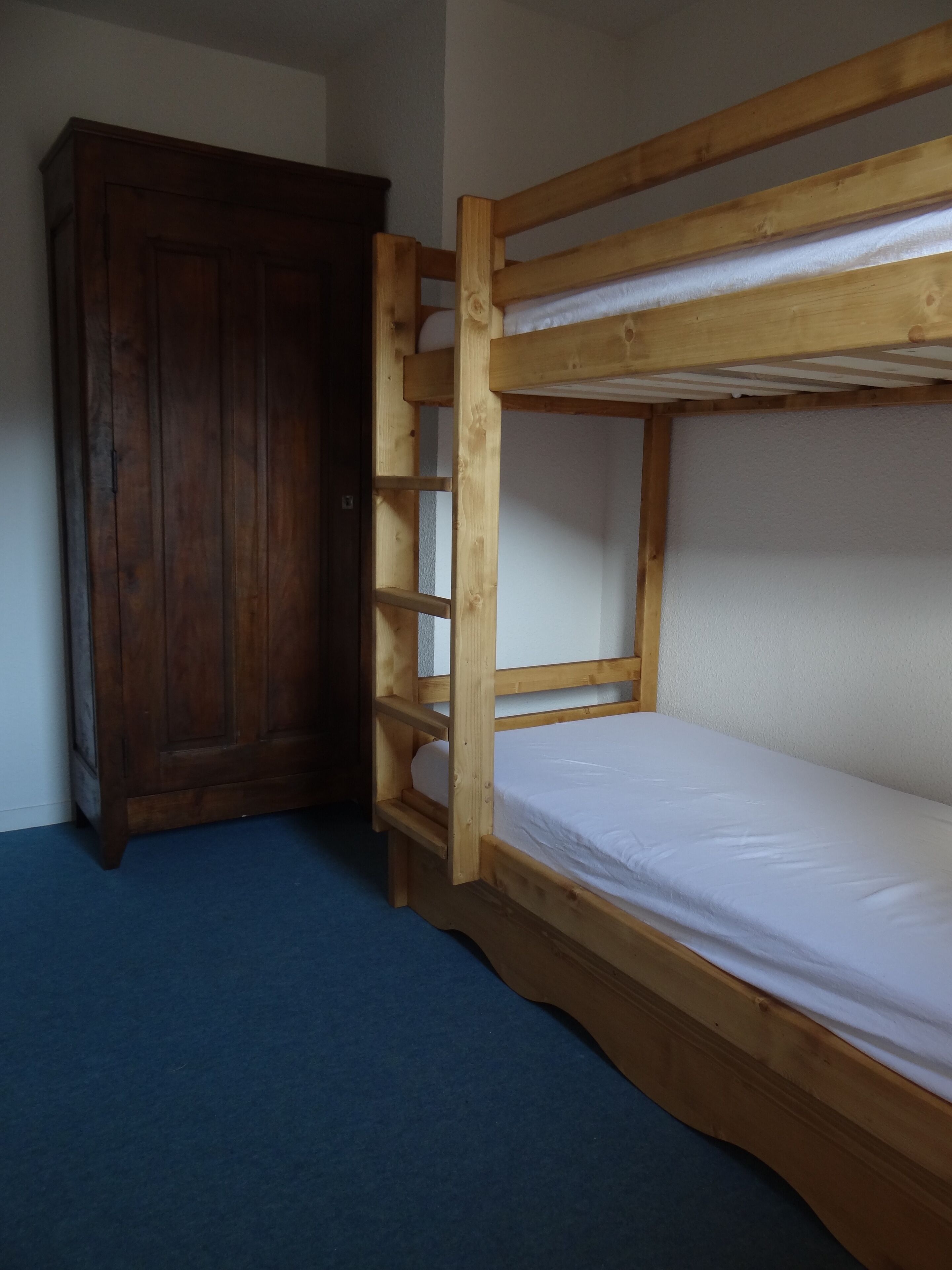 A bunk bed with a wooden frame and a single mattress.